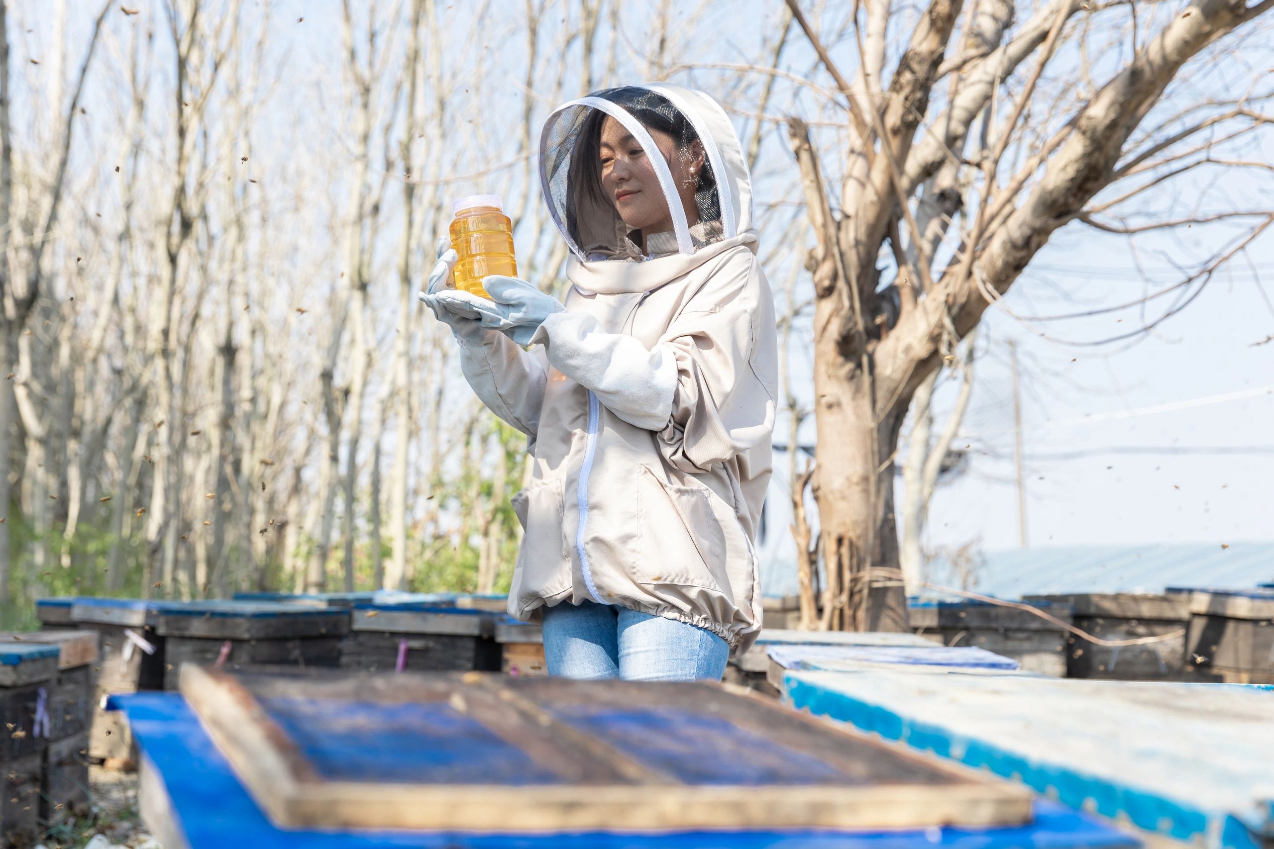 Woman beekeeper holding a jar of natural honey outdoors